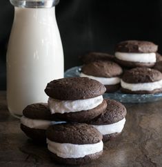 chocolate cookies and marshmallows on a table next to a bottle of milk