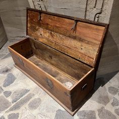 an old wooden box sitting on top of a stone floor next to a brick wall