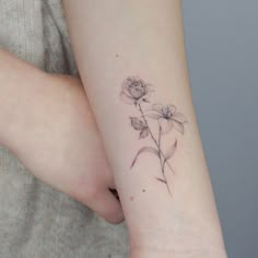 a woman's arm with a flower tattoo on the left side of her arm