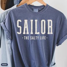 This sailing shirt makes a totally unique sailing gift for sailors, sailboat owners and lovers of all things nautical! Grab this Comfort Colors® tee today while it's on sale! Delivery Times: ◦ Production: 1 business day (avg.)  ◦ Shipping: 3 business days (avg.) Overview: ◦ Comfort Colors® branded retro t-shirt with muted vintage-style colors & a relaxed fit ◦ Pre-shrunk, ethically-sourced, 100% ring-spun American cotton ◦ Relaxed fit with the option to size up for an"oversized" or "shirt-dress" Blue Cotton Tops For Boating, Nautical Style Cotton Top In Sail Color, Nautical Style Sail Color Short Sleeve Tops, Nautical Cotton Tops For Boating, Nautical Short Sleeve Top In Sail Color, Nautical Cotton Top For Boating, Nautical Cotton Top In Sail White, White Nautical Tops For Sailing, Cotton Nautical Crew Neck Shirt