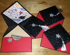 four cards with black and red envelopes on a wooden surface, one has a note attached to it