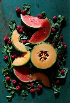 watermelon, raspberries and spinach are arranged on a blue surface