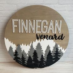 a wooden sign that says finnegan verard with trees in the background