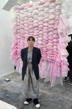 a woman standing in front of a large sculpture made out of plastic bags and other items