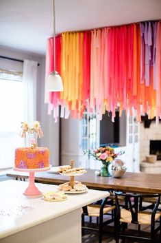 a cake on a table in a room with colorful streamers hanging from the ceiling