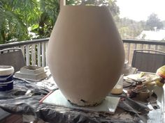 a large vase sitting on top of a table covered in paint and other things around it