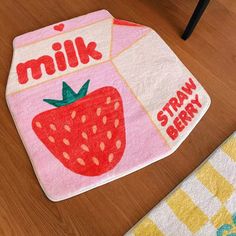 a close up of a towel on a wooden floor with a strawberry milk carton