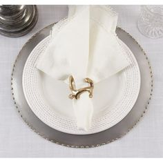 a white plate topped with a napkin and two silver plates next to each other on top of a table