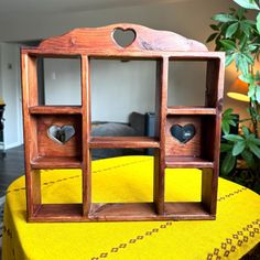 a wooden shelf with hearts cut out of it on a table in front of a couch