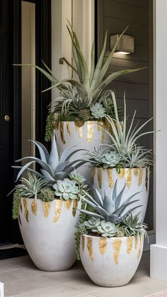 three white and gold planters with plants in them on the front step of a house