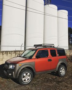 an orange and gray vehicle parked in front of some silos