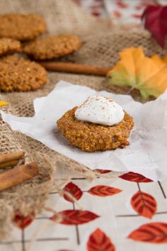 some cookies are sitting on a table with autumn leaves and cinnamon sticks in the background