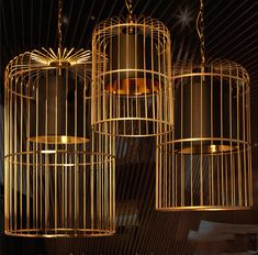 three golden birdcages hanging from the ceiling in a room with lights on them