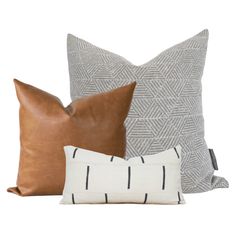 three pillows with different patterns on them, one is brown and the other is white