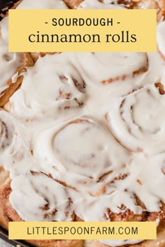 a cinnamon roll with white icing in a black pan on top of a table