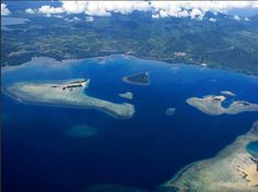 an aerial view of several islands in the ocean with blue water and clouds above them