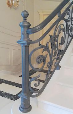 an iron stair railing in a house with black and white marble flooring on the ground