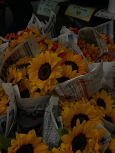 sunflowers are sitting in newspaper baskets on the ground