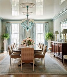 a dining room with a chandelier hanging from the ceiling next to a table and chairs