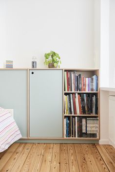 a bookshelf filled with lots of books on top of a hard wood floor