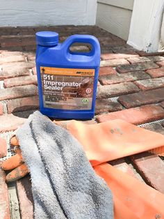 a bottle of cleaner sitting on top of a brick floor next to a glove and cloth