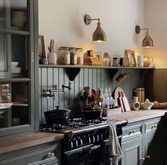 a kitchen with green cabinets and shelves filled with pots, pans and utensils