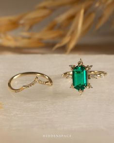 two gold rings with an emerald colored stone