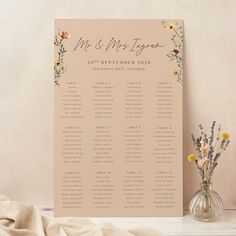 a wedding seating chart with flowers in vases on a table next to a sheet of paper