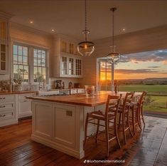 a large kitchen with wooden floors and white cabinetry is illuminated by the setting sun