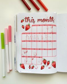 an open planner with strawberries on it and the words this month written in red