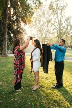 a man and woman standing in the grass holding clothes