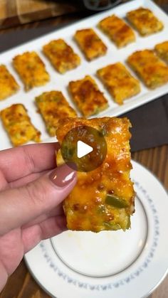 a person holding up a piece of food on a plate with other foods in the background