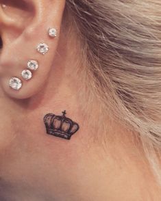 a woman's behind the ear tattoo with a crown on her left side ribcage