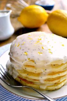 a stack of pancakes on a plate with lemons in the background