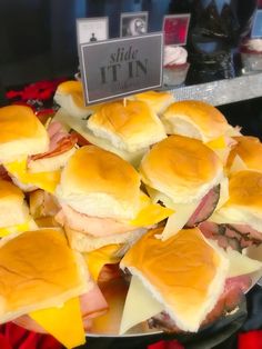 a plate full of ham and cheese sliders on display in a store front window