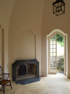 an empty room with a fireplace and chair