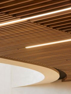 the ceiling is made of wood and has curved lights above it, along with white walls