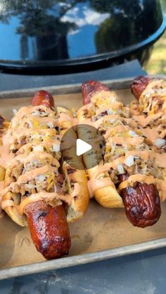 several hot dogs covered in toppings on a grill