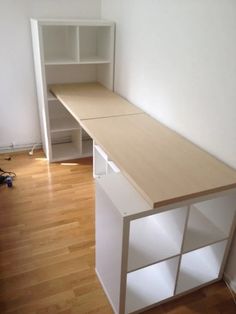 an empty room with a desk and bookcase in the corner, next to a hard wood floor