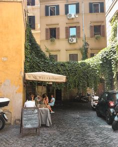 people are sitting at an outdoor cafe in the middle of a cobblestone street