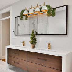 a bathroom with two sinks and a mirror on the wall next to it is decorated with greenery