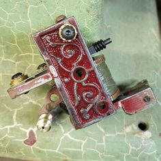 a red and silver lighter sitting on top of a green table next to a bottle opener