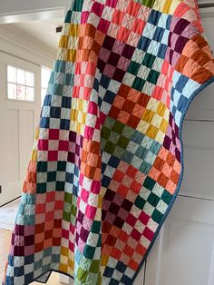 a multicolored quilt hanging from the side of a door