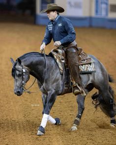 a man riding on the back of a black horse in an arena at a rodeo