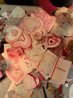 a table topped with lots of valentine's day greeting cards and paper hearts on top of each other