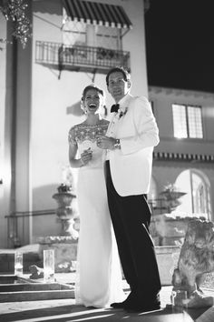 a man and woman standing next to each other in front of a building