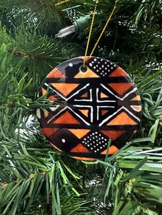 an ornament hanging from a christmas tree with black and orange designs on it