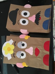 two brown paper bags with faces and flowers on them sitting on top of a table