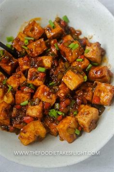 a white bowl filled with tofu and green onions