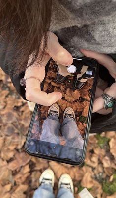 a person holding an iphone with their feet on the ground in front of them and looking down